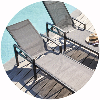 Sonnenliegen aus grauem Textilgewebe aufgestellt am Poolrand